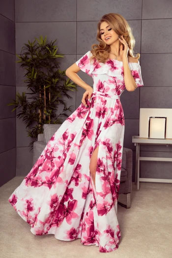 Modelka prezentuje elegancką sukienkę w kwiaty, która zachwyca swoim zwiewnym krojem i subtelnym rozcięciem. Ta kwiecista sukienka to idealny wybór na letnie przyjęcia, dodając lekkości i kobiecego wdzięku.