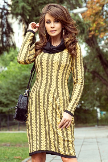 Modelka prezentuje elegancką sukienkę z wzorem w złote liście, która idealnie podkreśla sylwetkę. Sukienka z wzorem w złote liście jest doskonałym wyborem na jesienne spacery, dodając stylu i klasy każdej stylizacji.