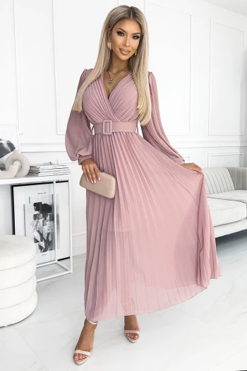 Modelka prezentuje elegancką sukienkę plisowaną, która podkreśla kobiecą sylwetkę dzięki dopasowanemu paskowi w talii. Sukienka plisowana w delikatnym odcieniu różu idealnie sprawdzi się na wyjątkowe okazje, dodając szyku i klasy każdej stylizacji.
