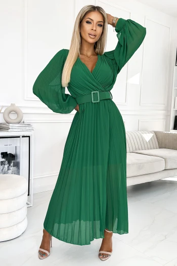 Modelka prezentuje elegancką zieloną sukienkę maxi z plisowanym dołem, która idealnie podkreśla sylwetkę. Sukienka maxi z paskiem w talii dodaje stylizacji szyku i klasy, doskonale sprawdzając się na wyjątkowe okazje.