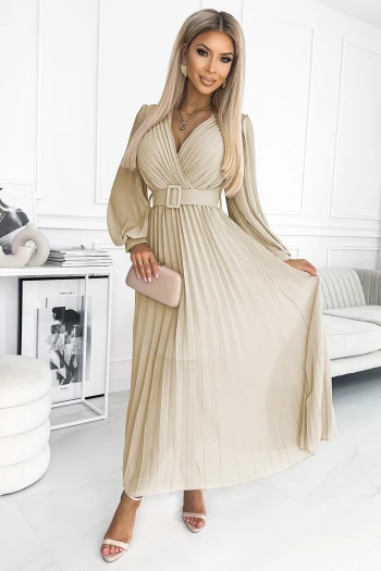 Modelka prezentuje elegancką sukienkę plisowaną, która podkreśla kobiecą sylwetkę i dodaje szyku każdej stylizacji. Sukienka plisowana z paskiem w talii idealnie nadaje się na wyjątkowe okazje, łącząc klasykę z nowoczesnym stylem.