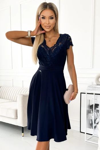 Kobieta na zdjęciu prezentuje elegancką sukienkę z koronkową górą, która podkreśla jej szykowny styl. Ta sukienka z koronką doskonale łączy klasykę z nowoczesnością, idealnie nadając się na wyjątkowe okazje.