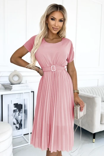 Modelka prezentuje elegancką sukienkę plisowaną w delikatnym odcieniu różu, która idealnie podkreśla kobiecą sylwetkę. Sukienka plisowana z paskiem dodaje stylizacji klasy i subtelnego uroku, doskonała na wyjątkowe okazje.