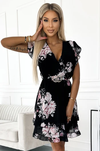Kobieta na zdjęciu prezentuje elegancką sukienkę w kwiaty, która idealnie podkreśla jej sylwetkę. Sukienka w kwiaty wyróżnia się delikatnym wzorem i subtelnym krojem, dodając stylizacji lekkości i kobiecości.