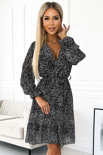 Modelka prezentuje elegancką sukienkę w panterkę, która idealnie podkreśla sylwetkę dzięki wiązaniu w talii. Ta sukienka w panterkę z długimi rękawami to doskonały wybór na wieczorne wyjścia, dodając stylu i pewności siebie.