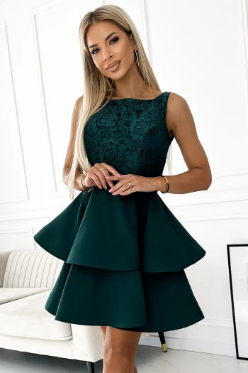 Modelka prezentuje elegancką sukienkę z falbanami, która podkreśla kobiecą sylwetkę i dodaje stylizacji wyjątkowego charakteru. Sukienka z falbanami w kolorze głębokiej zieleni idealnie sprawdzi się na wieczorne wyjścia, łącząc klasykę z nowoczesnym designem.