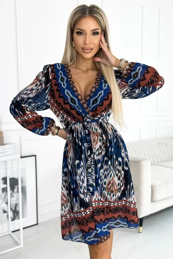 Modelka prezentuje elegancką sukienkę Boho, która wyróżnia się kolorowym, etnicznym wzorem i przewiewnym materiałem. Sukienka Boho z długimi rękawami i wiązaniem w talii doskonale podkreśla sylwetkę, dodając stylizacji lekkości i swobody.
