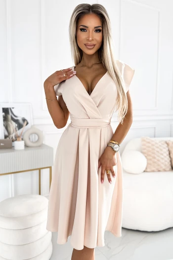 Kobieta na zdjęciu prezentuje elegancką sukienkę midi w odcieniu pudrowego różu, która podkreśla jej sylwetkę dzięki dopasowanemu krojowi i delikatnemu dekoltowi. Sukienka midi z krótkim rękawem idealnie sprawdzi się na wyjątkowe okazje, dodając stylizacji klasy i subtelności.