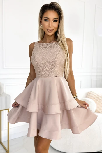 Modelka prezentuje elegancką sukienkę koronkową, której delikatny różowy odcień podkreśla kobiecość i subtelność stylizacji. Sukienka koronkowa z falbanami dodaje lekkości i ruchu, idealnie sprawdzając się na wyjątkowe okazje.