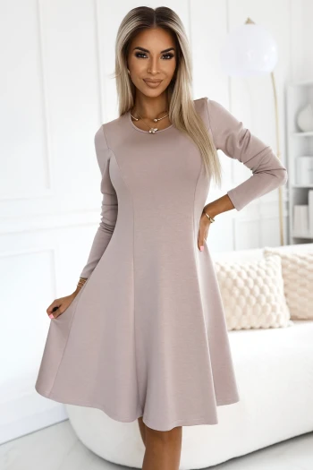 Kobieta na zdjęciu prezentuje elegancką sukienkę z długim rękawem w odcieniu beżu, która podkreśla jej sylwetkę i dodaje klasy. Sukienka z długim rękawem jest idealna na każdą okazję, łącząc wygodę z wyrafinowanym stylem.