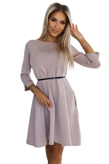 Kobieta na zdjęciu prezentuje elegancką sukienkę z długim rękawem, która idealnie podkreśla sylwetkę dzięki subtelnemu paskowi w talii. Ta stylowa sukienka to doskonały wybór na różne okazje, łącząc klasyczny krój z nowoczesnym akcentem.
