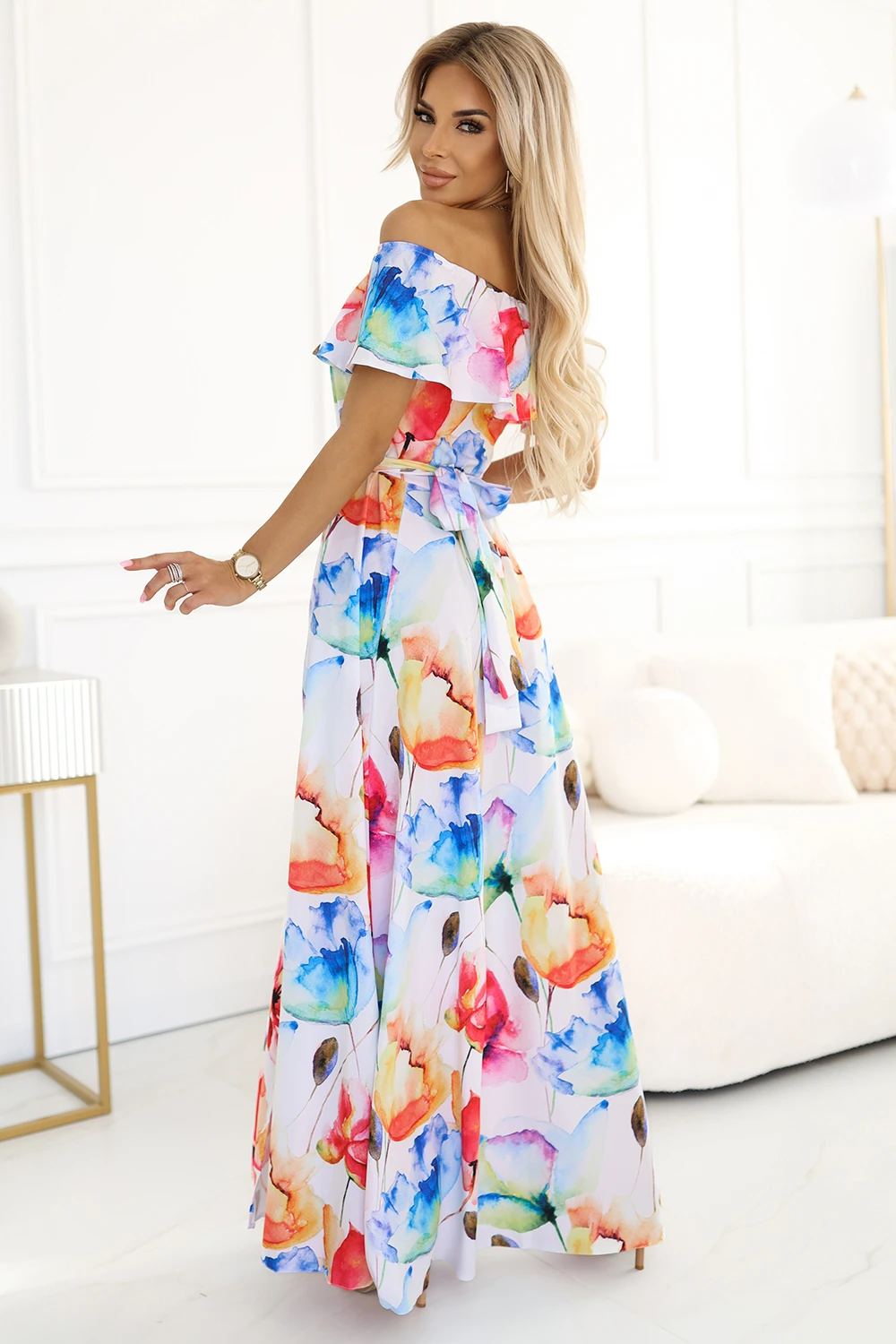 Modelka prezentuje elegancką sukienkę w kwiaty, która zachwyca żywymi kolorami i subtelnym krojem. Ta kwiecista sukienka idealnie podkreśla letni styl i dodaje kobiecości każdej stylizacji.