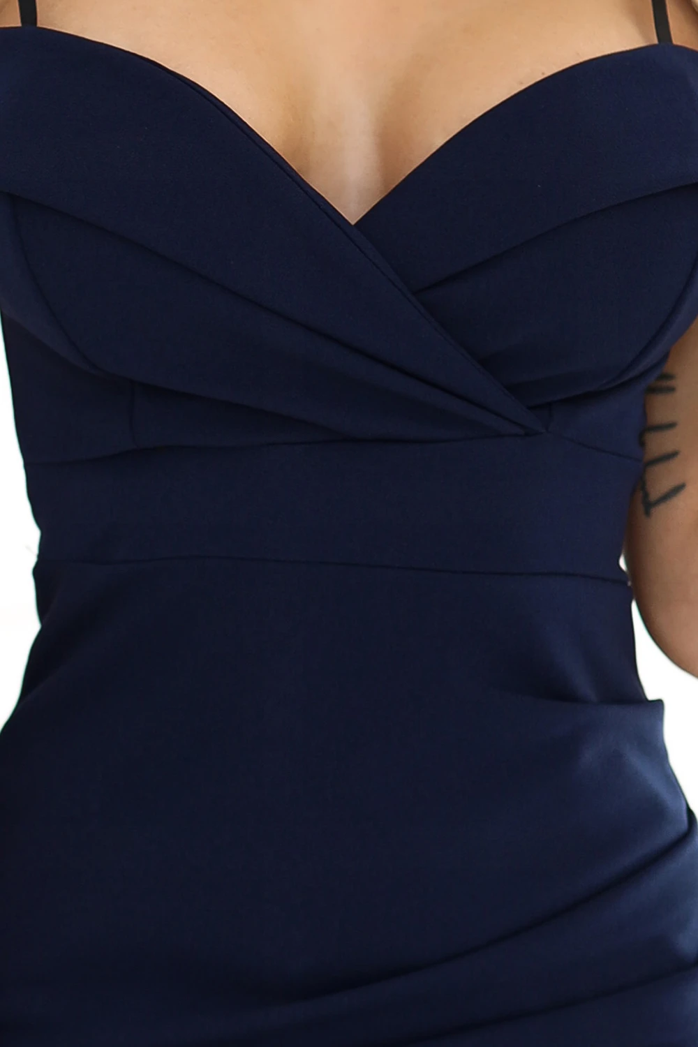 Modelka prezentuje elegancką sukienkę wieczorową w głębokim granatowym kolorze, która doskonale podkreśla sylwetkę. Sukienka wieczorowa charakteryzuje się subtelnym dekoltem i dopasowanym krojem, idealnym na wyjątkowe okazje.