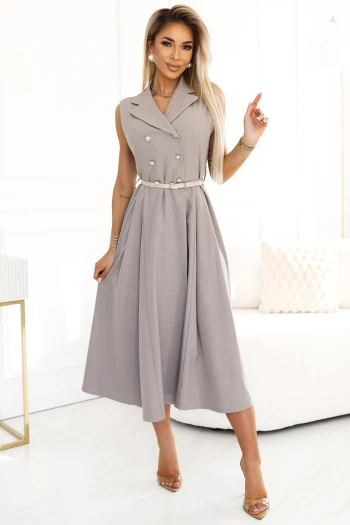Modelka prezentuje elegancką sukienkę midi z podwójnym rzędem guzików, która idealnie łączy klasykę z nowoczesnym stylem. Sukienka midi podkreśla sylwetkę dzięki subtelnemu paskowi w talii, dodając całości wyrafinowanego charakteru.