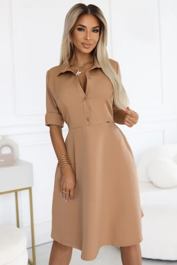 Kobieta na zdjęciu prezentuje elegancką sukienkę koszulową w kolorze camel, która doskonale podkreśla jej sylwetkę. Ta stylowa sukienka koszulowa z kołnierzykiem i rękawami 3/4 jest idealnym wyborem na każdą okazję.