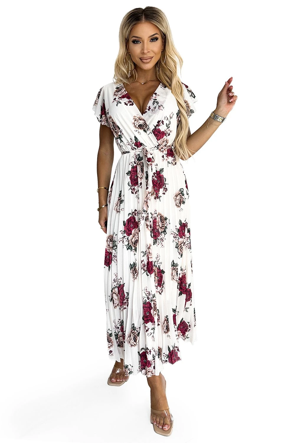 Kobieta na zdjęciu prezentuje elegancką sukienkę maxi w kwiaty, która doskonale podkreśla jej sylwetkę. Sukienka maxi w kwiaty emanuje lekkością i kobiecością, idealną na letnie dni i wieczorne wyjścia.