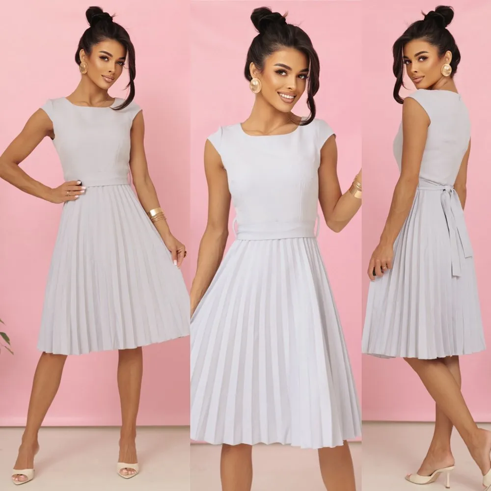 Modelka prezentuje elegancką sukienkę midi z plisowanym dołem, która doskonale podkreśla sylwetkę. Ta sukienka midi z plisami to idealny wybór na każdą okazję, łącząc klasykę z nowoczesnym stylem.