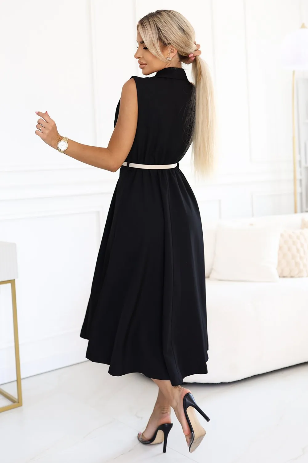 Kobieta na zdjęciu prezentuje elegancką sukienkę midi w kolorze czarnym, która idealnie podkreśla jej sylwetkę. Sukienka midi z delikatnym paskiem w talii dodaje stylizacji klasy i subtelności.