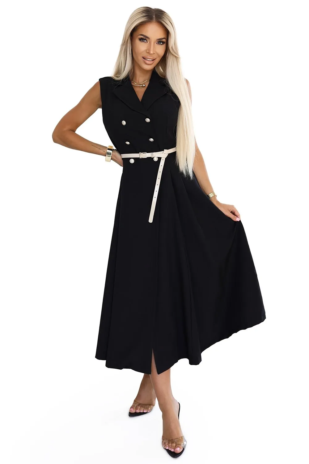 Kobieta na zdjęciu prezentuje elegancką czarną sukienkę midi z dwurzędowym zapięciem, która podkreśla jej sylwetkę. Sukienka midi jest uzupełniona subtelnym, jasnym paskiem, dodającym całości wyrafinowanego charakteru.