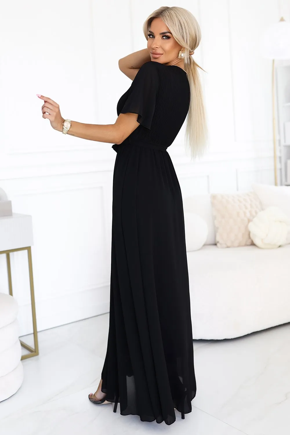 Modelka prezentuje elegancką sukienkę maxi, która doskonale podkreśla sylwetkę i dodaje klasy każdej stylizacji. Ta czarna sukienka maxi to idealny wybór na wieczorne wyjścia, łącząc w sobie szyk i wygodę.