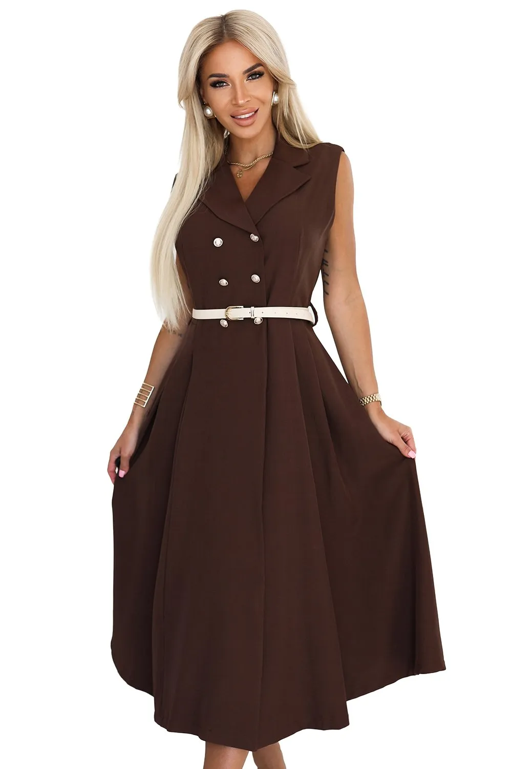 Modelka prezentuje elegancką sukienkę midi w kolorze czekoladowym, która wyróżnia się klasycznym krojem z podwójnym rzędem guzików. Sukienka midi jest uzupełniona stylowym, jasnym paskiem, który podkreśla talię, dodając całości wyrafinowanego charakteru.