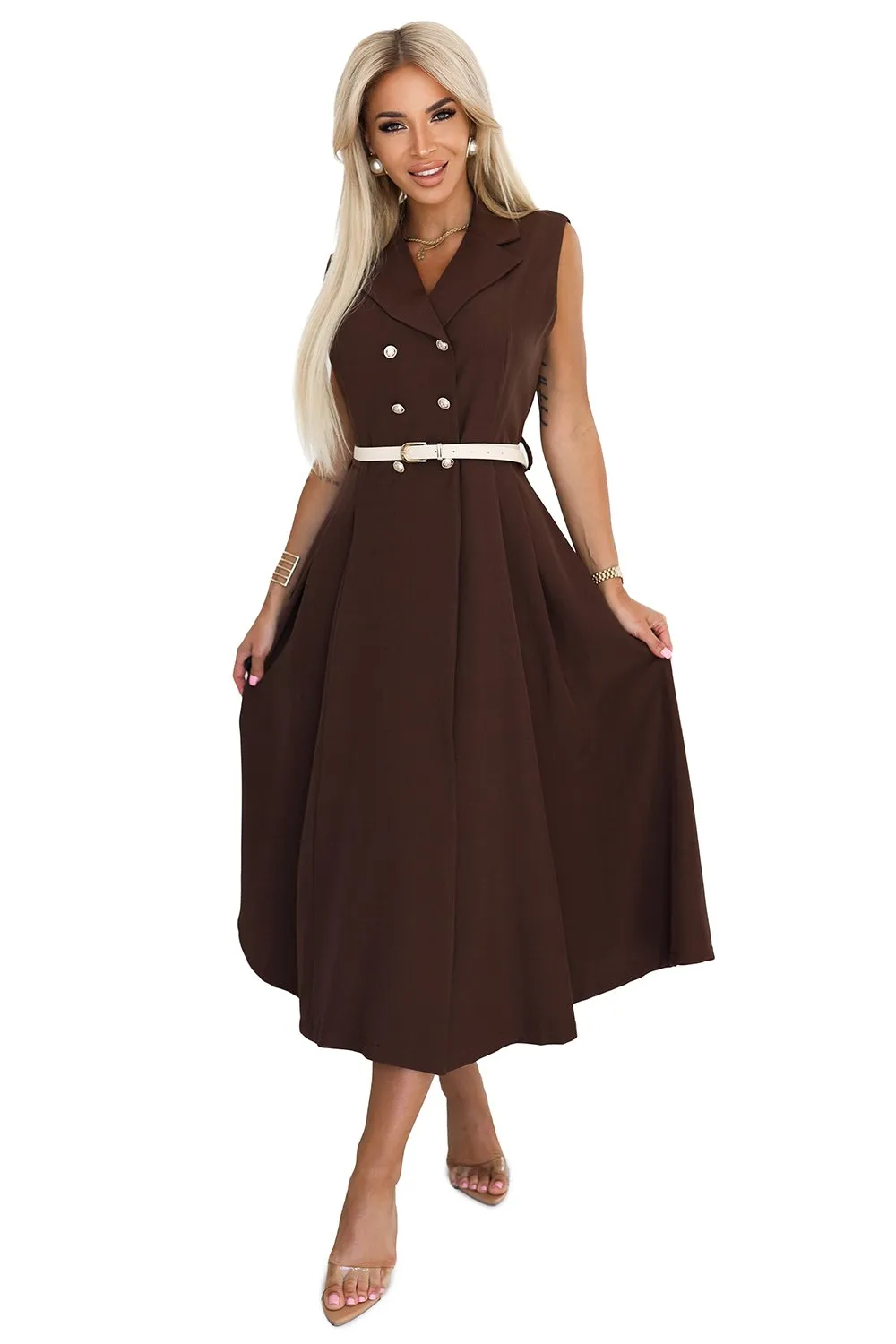 Kobieta na zdjęciu prezentuje elegancką sukienkę midi w kolorze czekoladowym, która idealnie podkreśla jej sylwetkę. Sukienka midi jest ozdobiona stylowymi guzikami i uzupełniona kontrastowym paskiem, dodającym całości szyku i klasy.