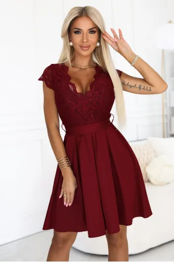 Modelka prezentuje elegancką sukienkę koronkową w głębokim odcieniu czerwieni, która idealnie podkreśla sylwetkę. Sukienka koronkowa z delikatnym wzorem i rozkloszowanym dołem dodaje szyku i kobiecości każdej stylizacji.