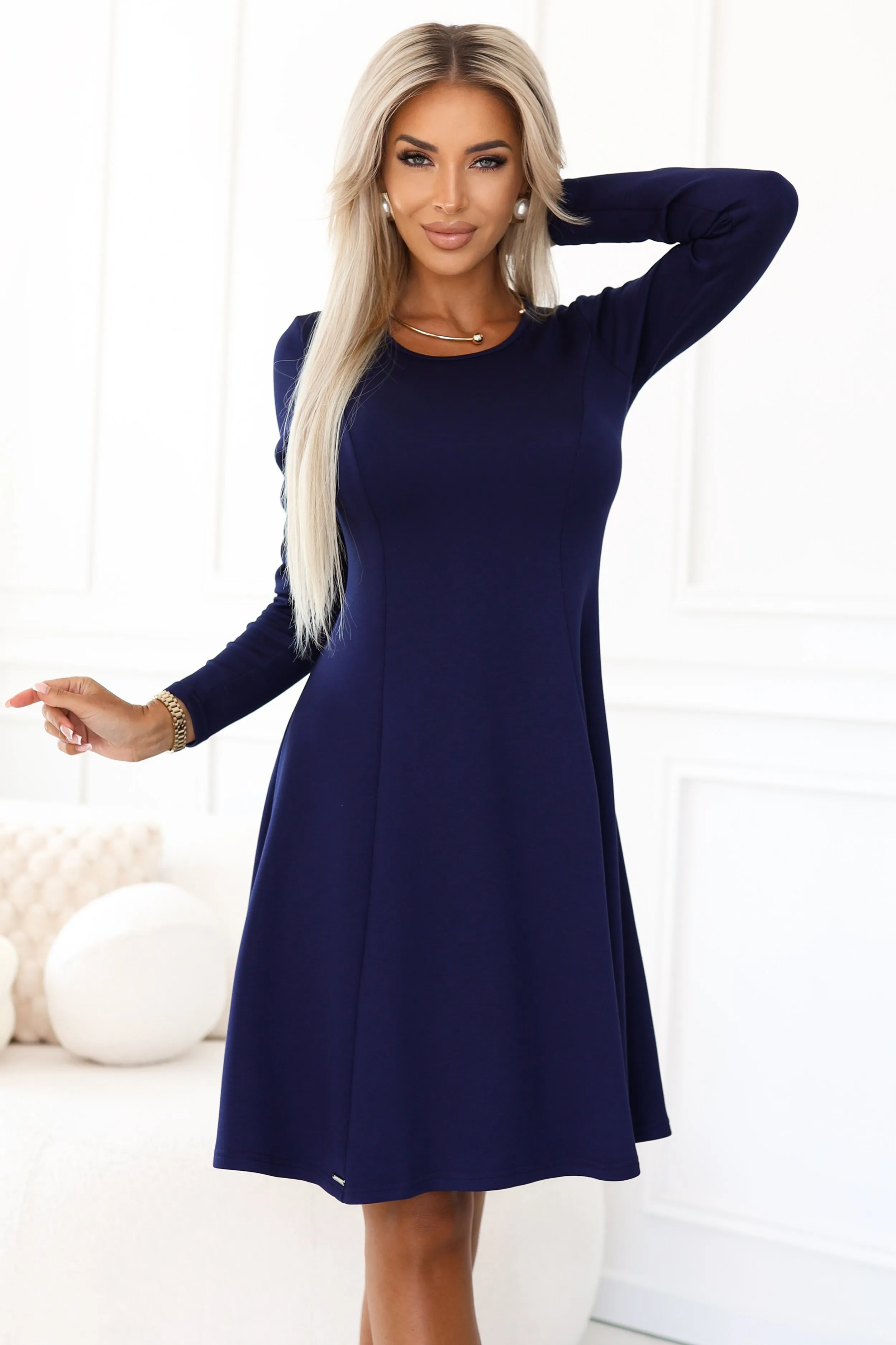 Modelka prezentuje elegancką sukienkę Paula w głębokim odcieniu granatu, która idealnie podkreśla jej sylwetkę. Sukienka Paula z długim rękawem to doskonały wybór na każdą okazję, łącząc w sobie klasykę i nowoczesność.