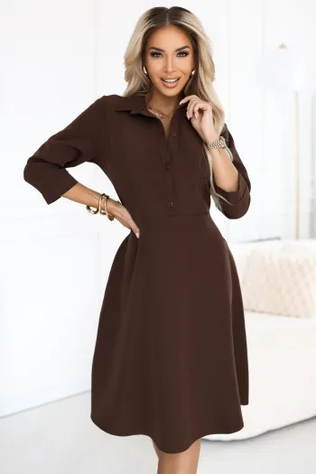 Modelka prezentuje elegancką sukienkę midi w kolorze czekoladowym, która doskonale podkreśla sylwetkę i dodaje klasy każdej stylizacji. Sukienka midi z kołnierzykiem i rękawem 3/4 to idealny wybór na formalne okazje, łącząc wygodę z wyrafinowanym stylem.