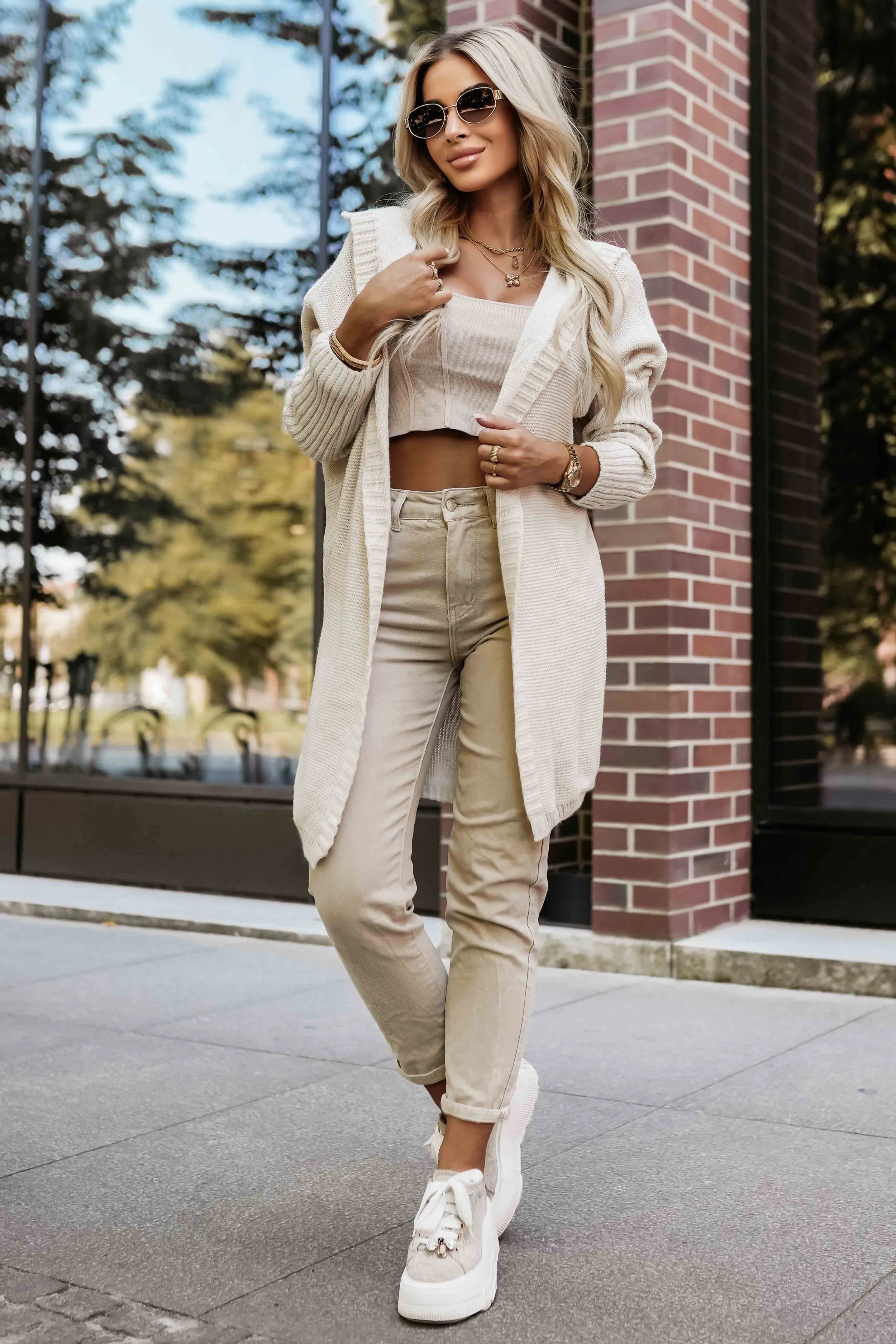 Modelka prezentuje stylowy kardigan beżowy, który idealnie komponuje się z casualowym zestawem na co dzień. Ten elegancki kardigan beżowy dodaje ciepła i klasy każdej stylizacji, podkreślając jednocześnie nowoczesny wygląd.