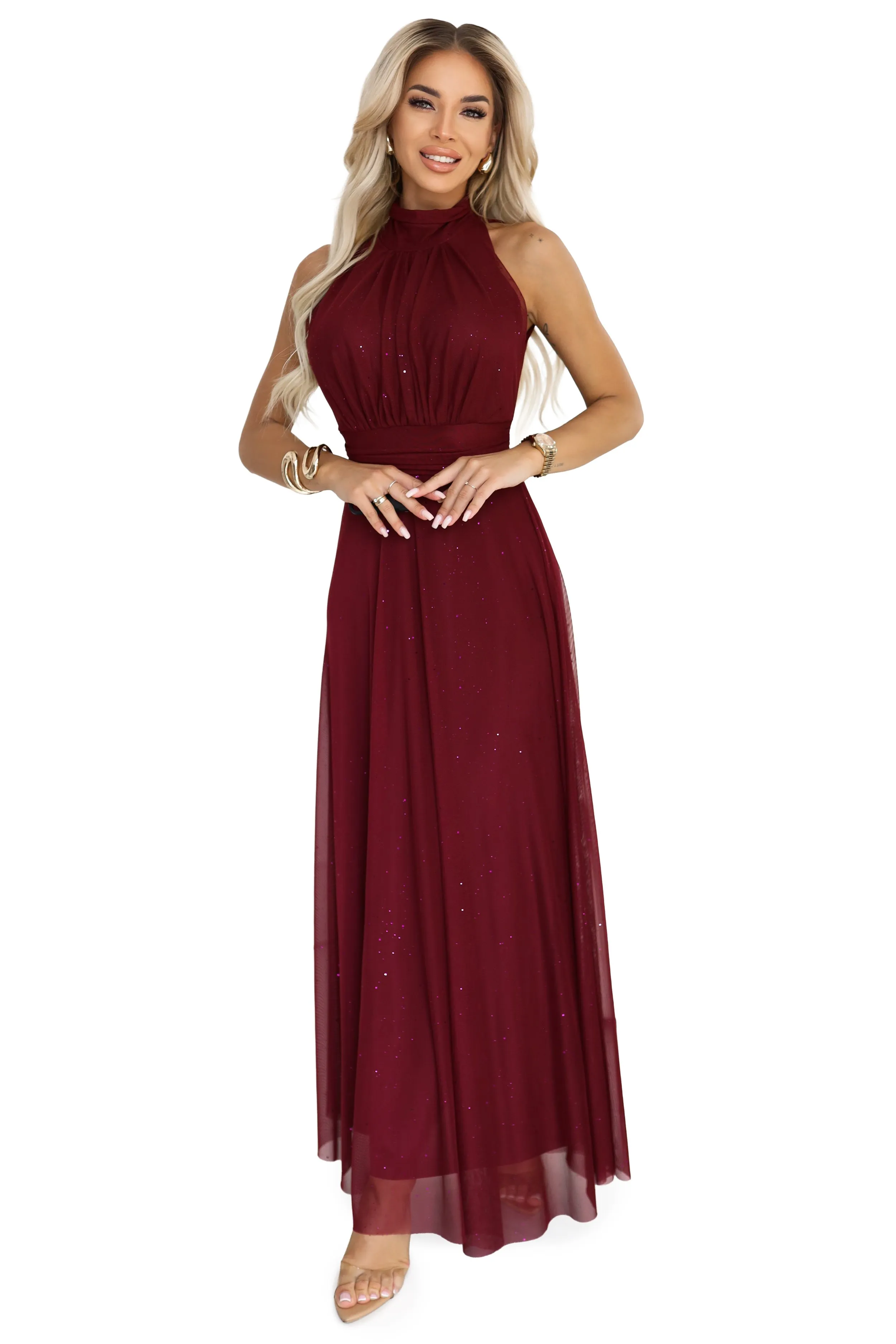 Modelka prezentuje elegancką, bordową sukienkę maxi, która doskonale podkreśla sylwetkę. Sukienka maxi z delikatnym połyskiem nadaje się idealnie na wyjątkowe okazje.